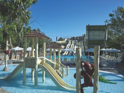 Zwembad met glijbanen en parasols onder een heldere lucht