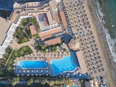 Luchtfoto van een hotel met zwembad, strandstoelen en directe toegang tot de zee.