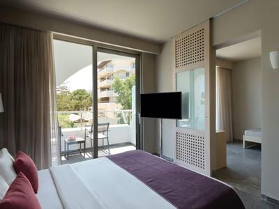 Modernes Hotelzimmer mit Balkon, Doppelbett und Blick auf die Außenanlage.