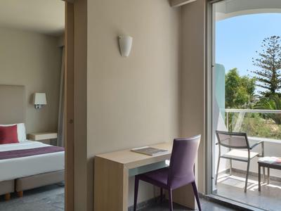 Blick auf einen Hotelzimmer-Schreibtisch mit Balkon und offenem Meerblick.