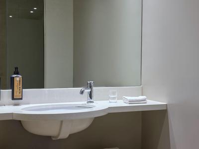 Moderner Badezimmerwaschtisch mit Spiegel, Wasserhahn und Pflegeprodukten.