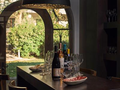 Ein gedeckter Holztisch mit Weinflaschen und Gläsern vor einem Bogenfenster mit Blick auf einen Garten.