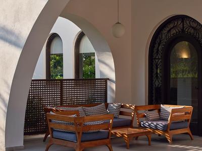 Gemütliche Sitzecke mit Holzmöbeln unter weißen Rundbögen im Freien.