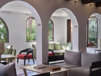 Innenraum einer stilvollen Lounge mit großen bogenförmigen Fenstern und gemütlichen Sitzbereichen.