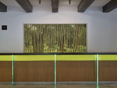 Rezeption mit Holzverkleidung und grüner Glasabtrennung, großes Fenster mit Waldsicht im Hintergrund