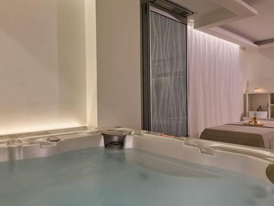 Moderner Raum mit Whirlpool und Bett, sanfte Beleuchtung erzeugt entspannte Atmosphäre.