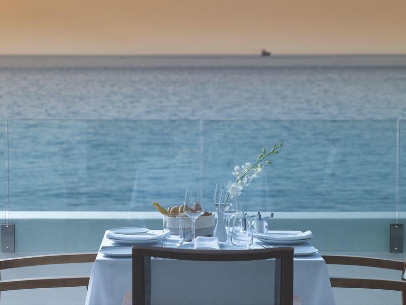 Een gedekte tafel met uitzicht op de blauwe zee en een verre horizon.