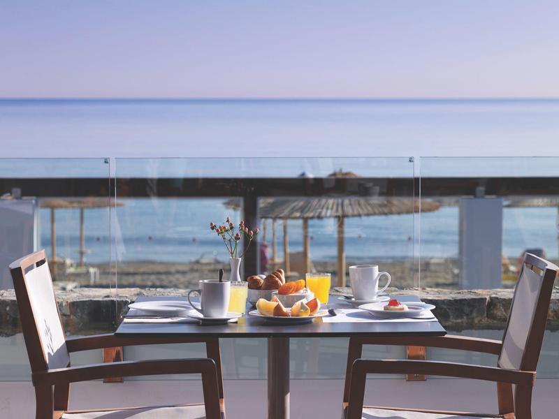 Een tafel voor twee met ontbijt op een terras met uitzicht op zee.