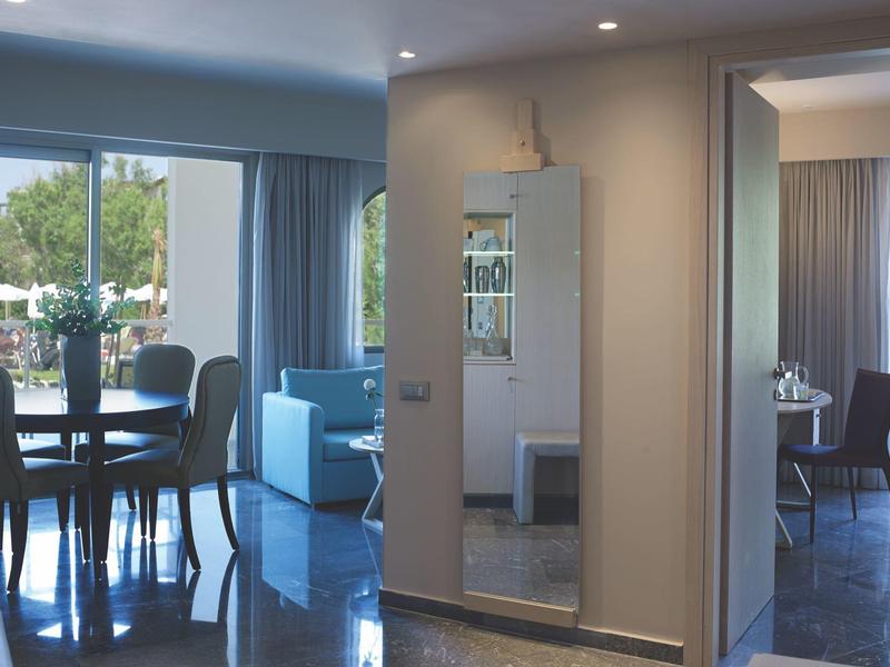 Moderne hotelkamer met eetgedeelte, zithoek en uitzicht op buitenzwembad.