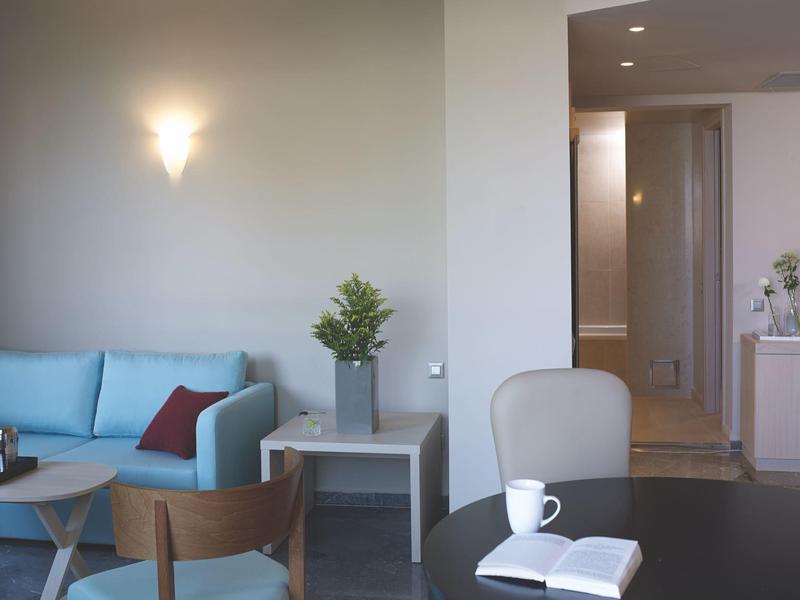 Modern ingerichte woonkamer met blauwe bank, stoelen en een tafel met kop en boek.