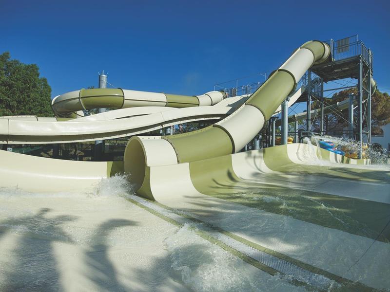 Groene en witte glijbaan in een waterpark onder een blauwe lucht
