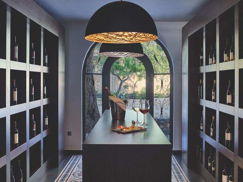 Moderne wijnkelder met donkere planken en centraal eiland onder een grote hanglamp