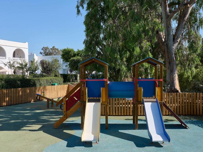 Kinderspeelplaats met twee glijbanen en houten constructies in de hoteltuin