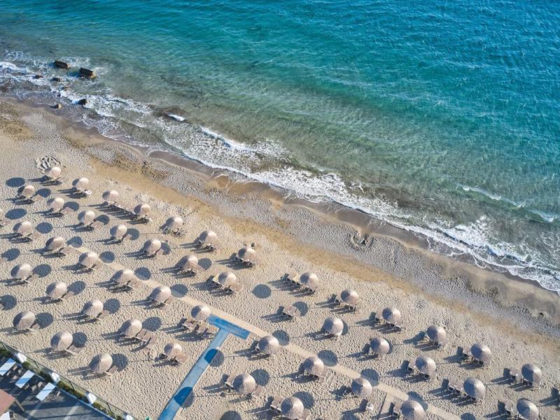 Strand met parasols en stoelen bij helderblauwe zee.