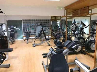 Gym room with various exercise machines and wooden flooring in a hotel.