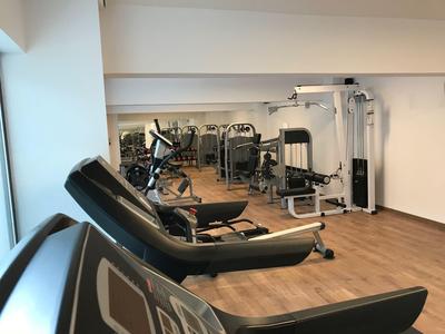 Modern gym with treadmills and strength machines on wooden floor