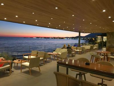 Terrace with tables and chairs by the sea at sunset
