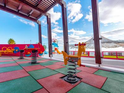 Kolorowy plac zabaw na zewnątrz z wiosennymi zwierzętami na sprężynach, otoczony balustradą.