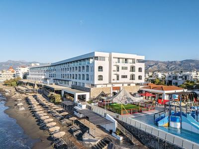 Modern hotel by the sea with sun loungers and kids' pool in sunny weather.