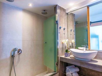 Nowoczesna kabina prysznicowa ze szklaną ścianą, słuchawką i umywalką w hotelowej łazience.