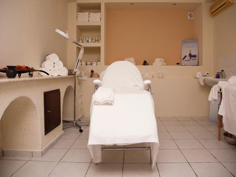 Prosto umeblowany pokój zabiegowy z leżanką i półkami z ręcznikami do zabiegów wellness.