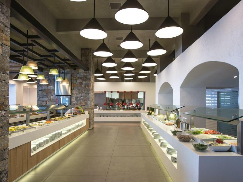 Nowoczesna restauracja bufetowa z ciepłym oświetleniem, kamiennymi ścianami i szerokim wyborem potraw.