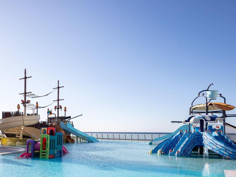 Park wodny z zjeżdżalniami i statkiem pirackim w basenie pod czystym niebem.