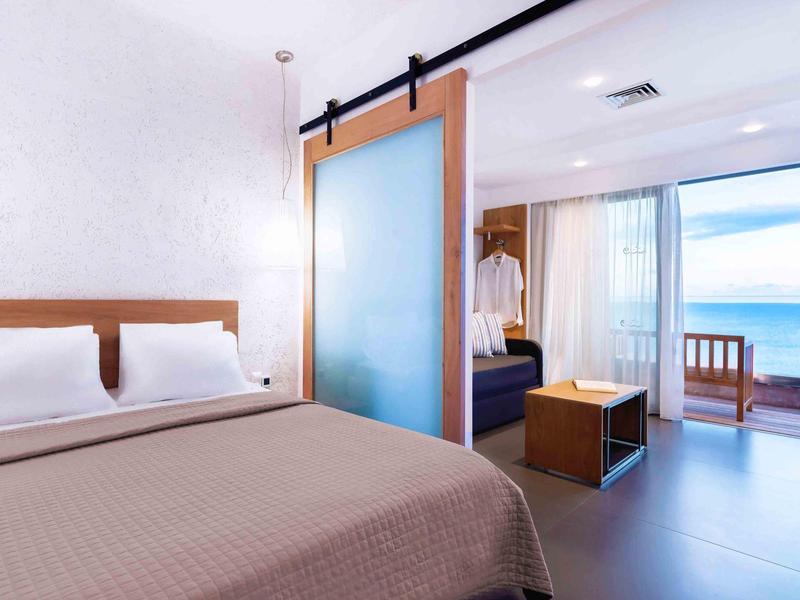 Nowoczesny pokój hotelowy z podwójnym łóżkiem i balkonem z widokiem na morze.