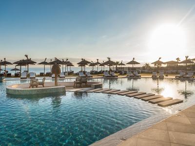Area piscina moderna con lettini e ombrelloni vicino all'acqua al tramonto