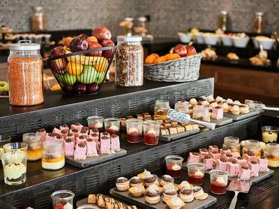 Buffet met diverse desserts en fruit in glazen en kommen.
