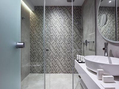 Moderne badkamer met mozaïektegels en grote glazen douche.
