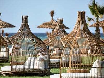 Lettini da spiaggia con coperture in vimini e palme su una spiaggia tropicale