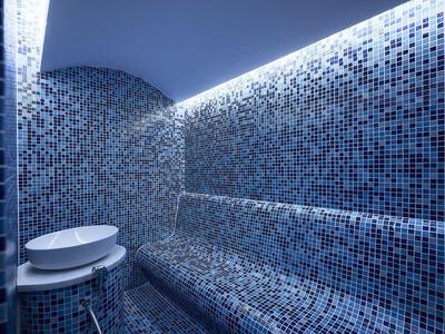 Moderne wellnessruimte met mozaïektegels en een plank voor accessoires.