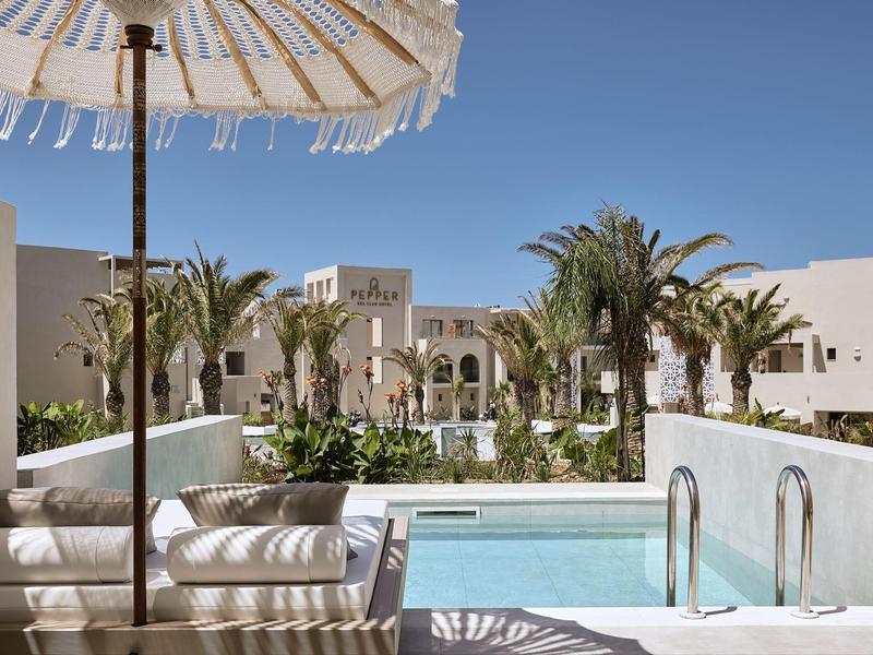 Luxe terras met zwembad, parasol en palmbomen in een rustige hotelsfeer.