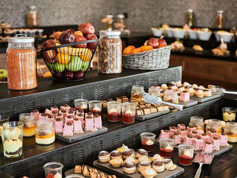 Buffet met diverse desserts en fruit in glazen en kommen.