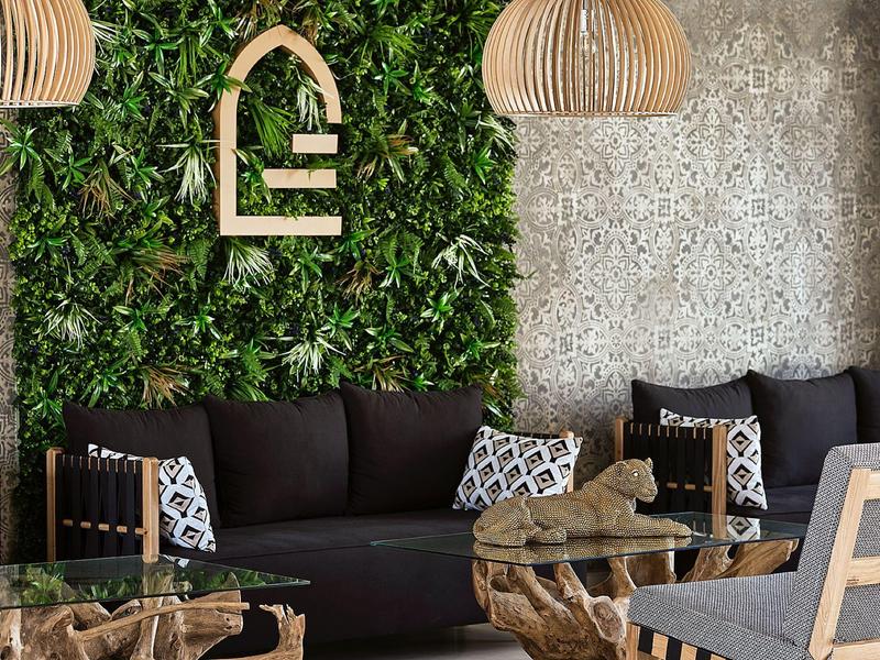 Moderne lounge met bank, houten tafel en groene plantmuur.