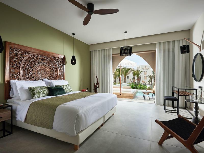 Lichte hotelkamer met groot bed, sierlijke wanddecoratie en uitzicht op een terras.