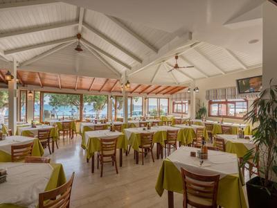 Restaurant lumineux avec de nombreuses tables dressées et des meubles en bois donnant sur une terrasse.