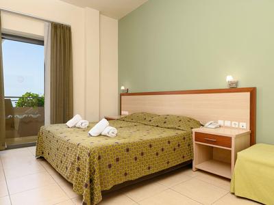 Chambre d'hôtel lumineuse avec lit double, couvre-lit vert et balcon