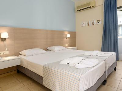 Chambre twin avec literie blanche nette et mobilier minimal.