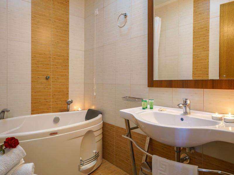 Salle de bain lumineuse avec baignoire, lavabo, grand miroir et serviettes.