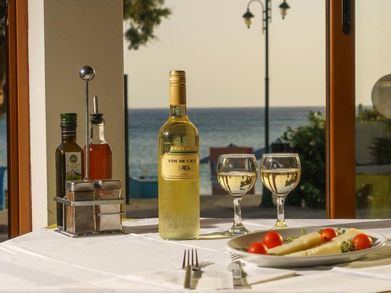 Une table dressée avec bouteille de vin, verres et décorations avec vue sur la mer.