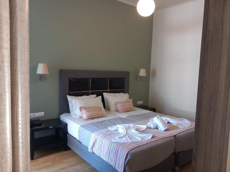 Habitación de hotel acogedora con dos camas unidas, mesas de noche y toallas decorativas.