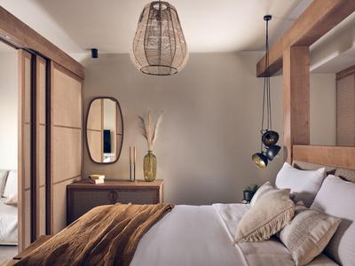 Gemütliches Schlafzimmer mit Holzmöbeln, großer Spiegel, ovalem Wandspiegel und Korblampe.