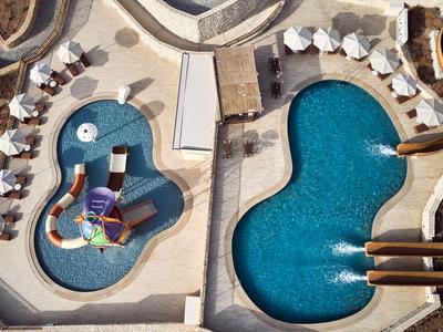 Zwei Pools, einer mit Wasserrutschen und Spielgeräten, der andere mit organischer Form und Fontänen.