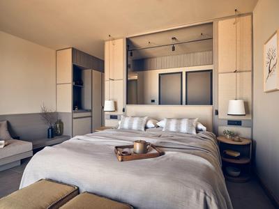 Modernes Schlafzimmer mit grauem Bett, Nachttischen, indirekter Beleuchtung und großem Wandbild.