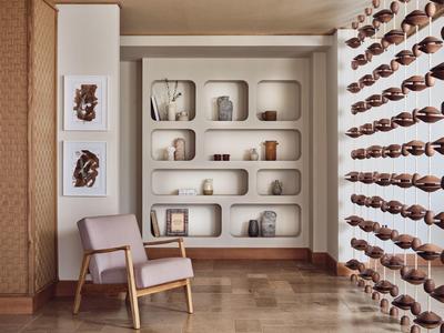 Moderner Raum mit eingebauten Regalen, dekorativen Objekten, Holzstuhl und Weinlager an der Wand.
