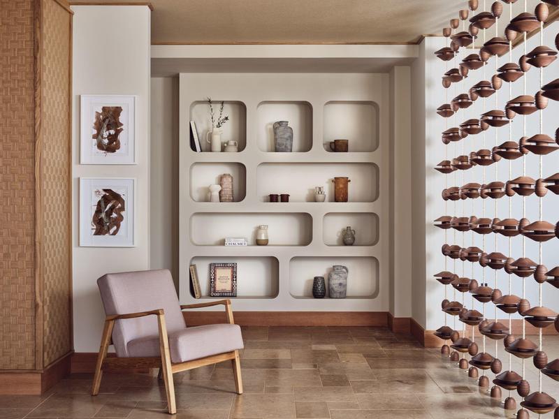 Cozy room with wooden chair, decorative shelves, and patterned glass wall creating warm atmosphere.