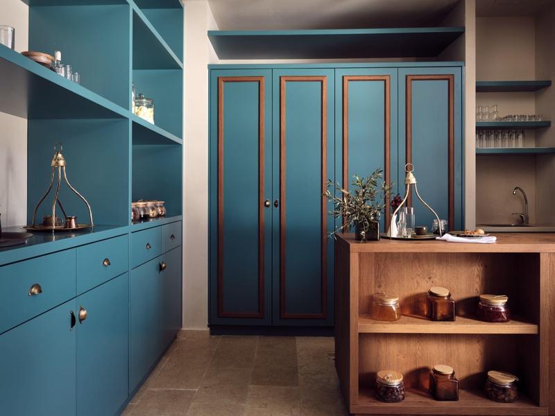 Modern kitchen with teal cabinets, wooden shelving, and decorative items on countertops.
