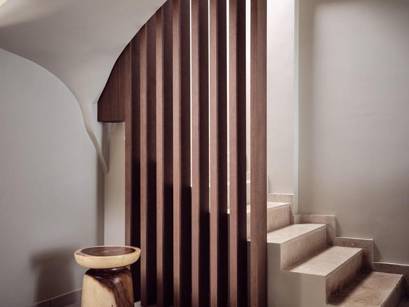 Modern interior with wooden vertical slats, small stool, and light stone steps.
